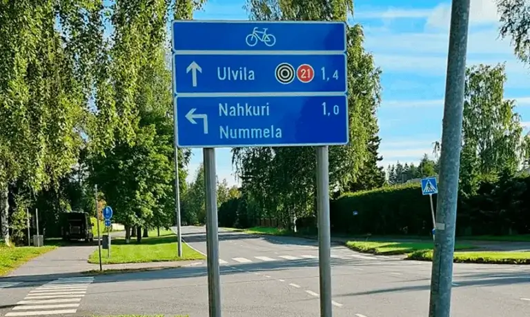 Porin pyöräilyreitin viitoitusopaste. Taustalla autotie.